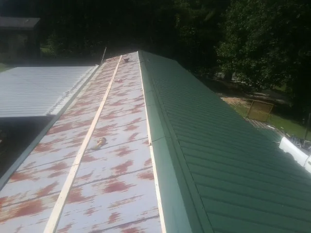 Old rusted panels beside newly installed green metal roofing — Wind Damage Roof Repair by Roofing Brothers in Hayward
