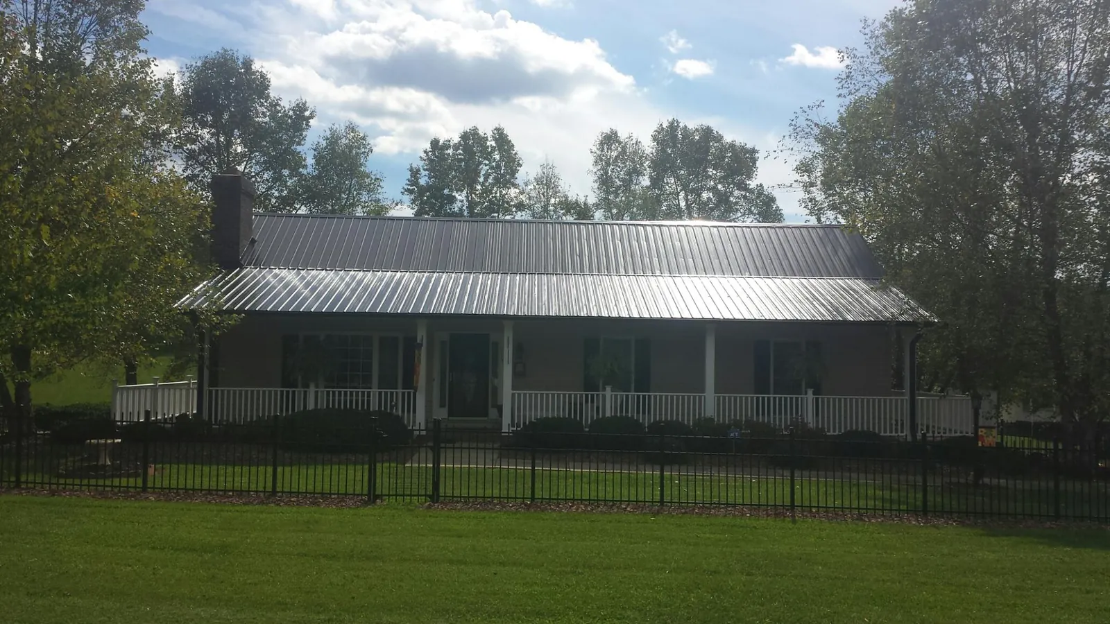 Gray metal roof on a brick ranch with a full width front porch — Gutter Guard Installation work by our crew in Hayward
