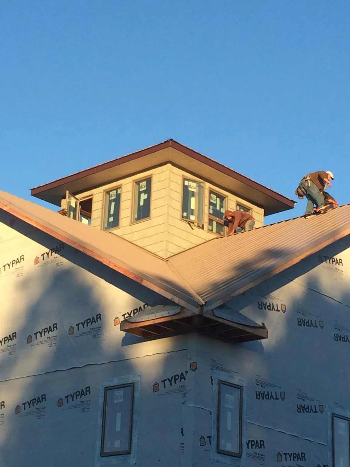 Roofers working around a rooftop cupola on a new metal roof at sunset — Roof Waterproofing in Hayward by Roofing Brothers